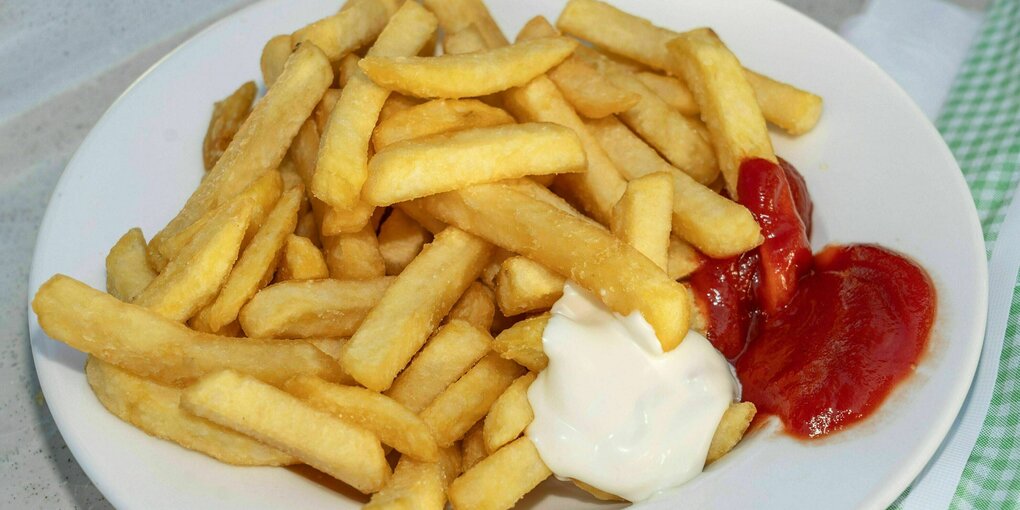 Pommes Frites mit Ketchup und Mayo auf einem Teller serviert