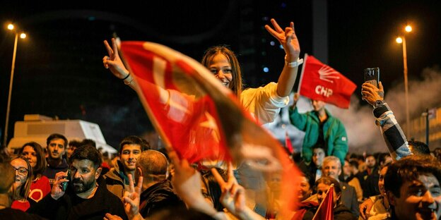 Eine Frau feiert auf den Schultern eines Mitfeiernden den Wahlsieg der CHP in Ankara, sie zeigt mit beiden Händen das Victory-Zeichen