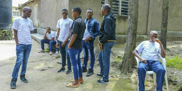 Junge Männer stehen zusammen in einem Hof und sprechen