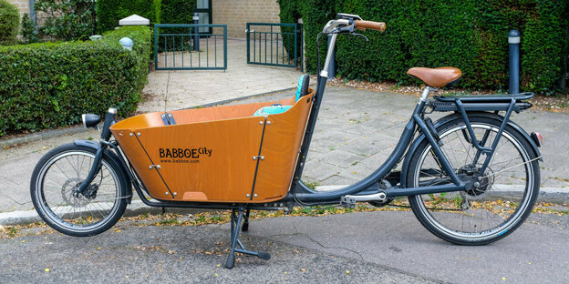 Ein Lasten-Fahrrad der Firma Babboe steht vor einem Haus.