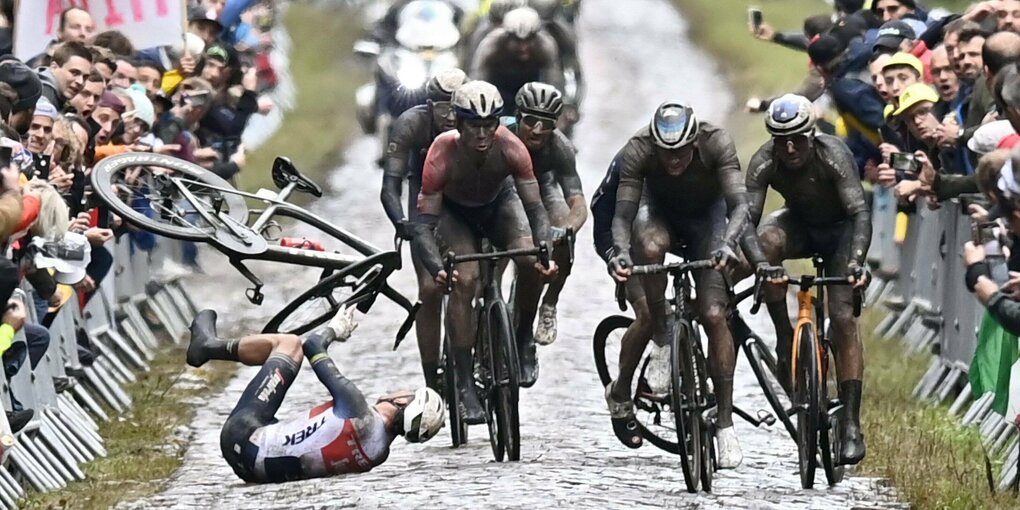 Ein Radfahrer liegt nach dem Sturz auf einer Kopfsteinpflasterstraße auf dem Rücken.