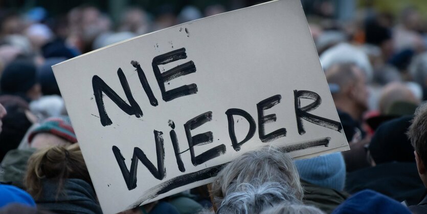 Das Bild zeigt ein Schild mit der Aufschrift "Nie wieder"