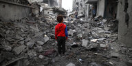 Ein Junge steht in einem Berg von Trümmern