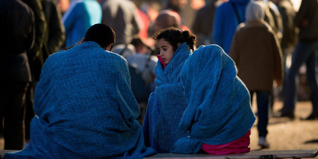 Flüchtlinge sitzen in Decken gewickelt
