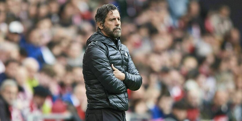 Der Trainer Quique Sanchez Flores steht mit ernster Miene und verschränkten Armen am Spielfeld