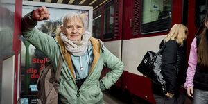 Eine Frau lehnt an einen Fahrscheinautomaten, rechts steht ein Bus