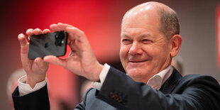 Olaf Scholz hantiert mit einem Handy.