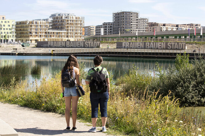 Zwei Frauen schauen über einen Fluß auf das andere Ufer.