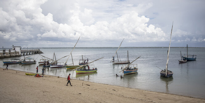 An einem Strand liegen kleine Fischerboote im Wasser.