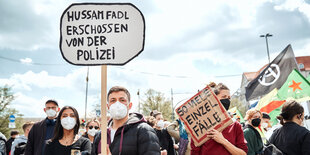 Menschen auf einer Demonstration; einer trägt ein Schild mit der Aufschrift "Hussam Fadl erschossen von der Polizei"