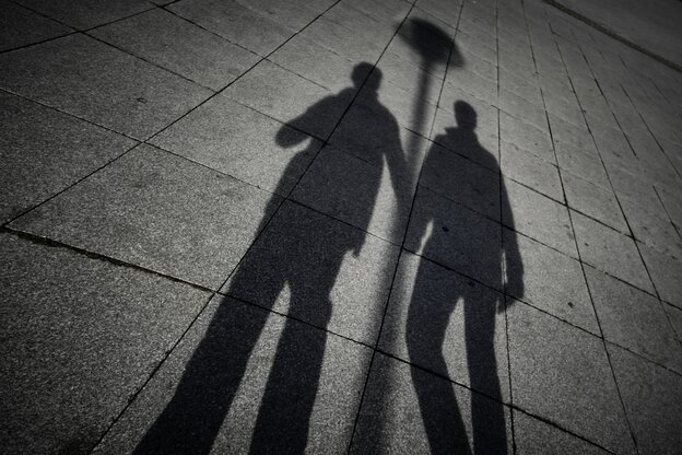 Zu sehen sind die Schatten von zwei Männern, die sich an der Hand halten.