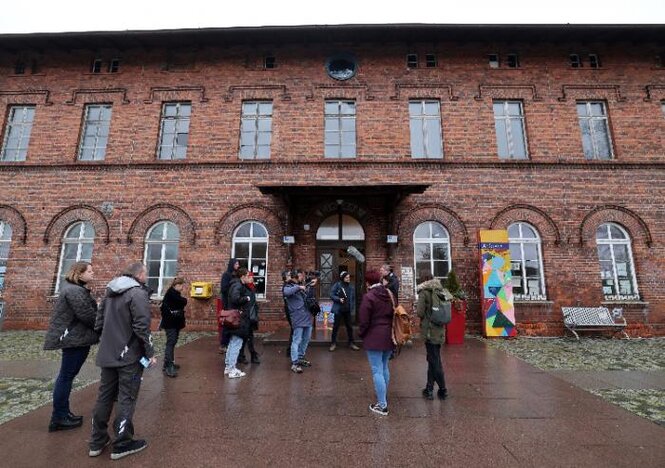 Bewohner Anklams sprechen vor dem Gebäude des Demokratiebahnhofs mit Reportern