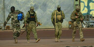 Vier schwer bewaffnete Soldaten laufen nebeneinender .