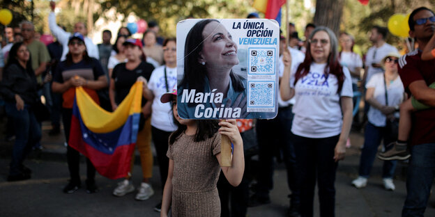 Demonstranten mit einem Schild, das das Gesischt von Maria Corina Machado zeigt