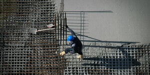 Ein Arbeiter ist auf einer Baustelle am Alexanderplatz beschäftigt, es wird Beton gegossen