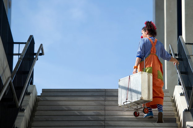 Eine Clownin steigt eine Treppe hoch.