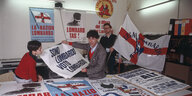 Der junge Umberto Bossi sitzt über Plakaten der Lega Nord an einem Tisch
