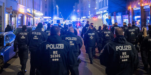 Polizisten und Polizeiautos mit Blaulicht in einer Straße bei Nacht