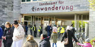 Menschen sitzen vor dem Landesamt für Einwanderung