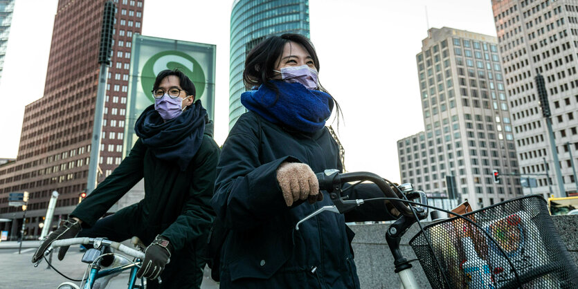 Zwei Japaner:innen mit Mundschutzmasken verlassenen den Potsdamer Platz mit Einkäufen.