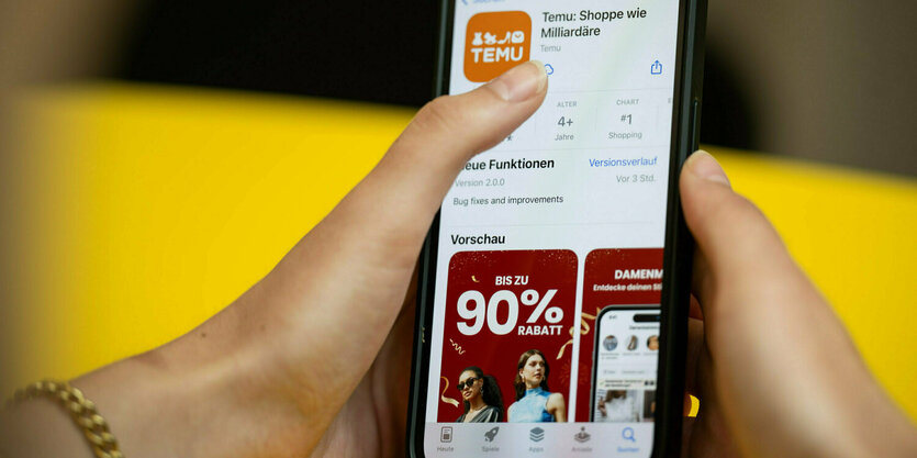Eine Person hält ein Telefon mit der App Temu in den Händen.