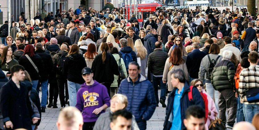 Viele Menschen schlendern eine Fußgängerzone entlang