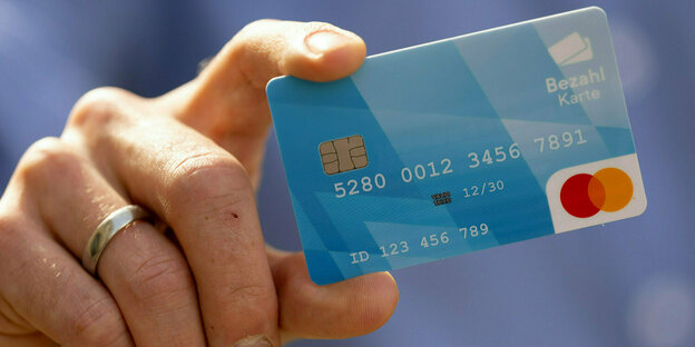 Eine Person hält während einer Pressekonferenz eine Bezahlkarte in der Hand.