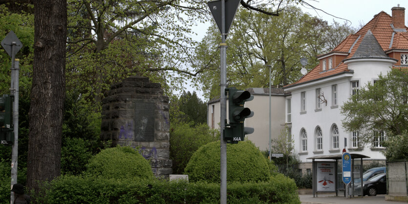 Ein Gedenkstein zwischen Büschen an einer Straßenkreuzung