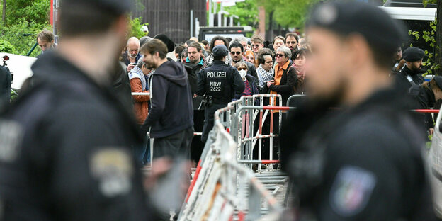 Berlin: Polizisten stehen vor der Veranstaltungshalle des Palästina-Kongress 2024 vor Teilnehmern, die darauf warten reingelassen zu werden.
