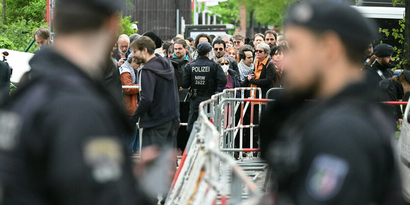 Berlin: Polizisten stehen vor der Veranstaltungshalle des Palästina-Kongress 2024 vor Teilnehmern, die darauf warten reingelassen zu werden.