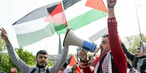 Zwei Demonstranten mit Megaphon vor palästinensischen Fahnen