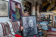 Eine Frau in dekorativem blumenbesticktem Outfit hat das Foto ihrer Großmutter auf dem Schoß