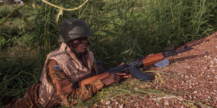 Ein Soldat aus Burkina Faso liegt in Tarnkleidung auf dem Boden.