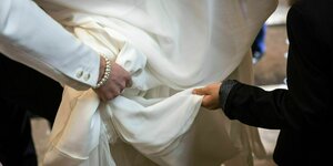 Zwei Hände an einem Brautkleid