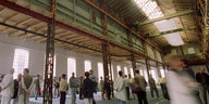 Menschen in der leerstehenden Schiffbauhalle der Rostocker Neptunwerft