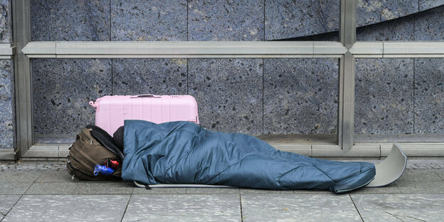 Eine obdachlose Person schläft auf der Straße.