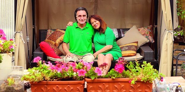Eine Frau und ein Mann sitzen in einer Hollywoodschaukel in einem Kleingarten