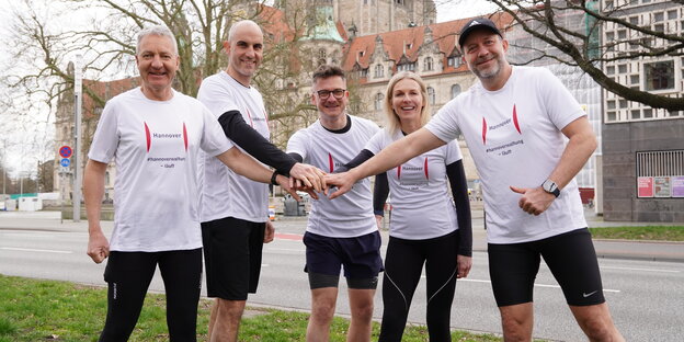 Oberbürgermeister Belit Onay posiert mit anderen Spitzenbeamten der Stadt vor dem Rathaus in den weißen Shirts, mit denen sie als Staffelläufer beim Hannover Marathon antreten wollen