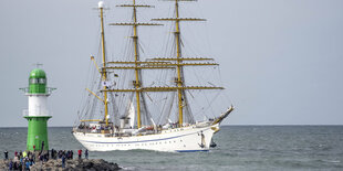 Die Gorch Fock fährt an einem Leuchtturm vorbei.