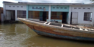 Ein Boot auf den Wassermengen und dahinter ist ein Haus