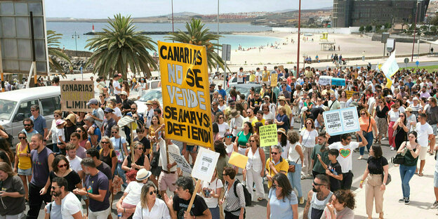 Protestierende gegen Massentourismus, im Hintergrund der Strand.