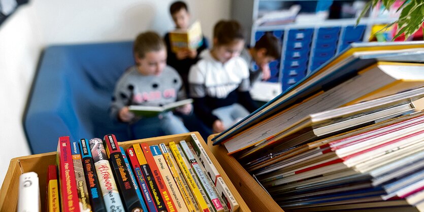 Drei Kinder sitzen auf einem blauen Sofa mit Büchern in der Hand