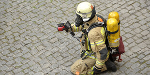 Ein knieender Feuerwehrmann auf dem Asphalt