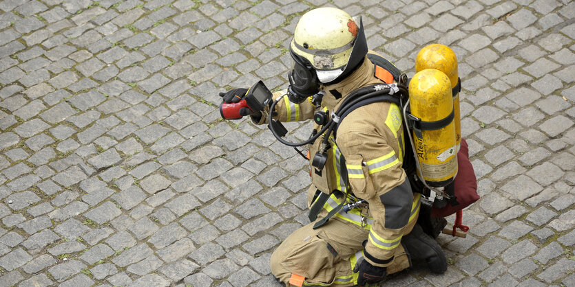 Ein knieender Feuerwehrmann auf dem Asphalt