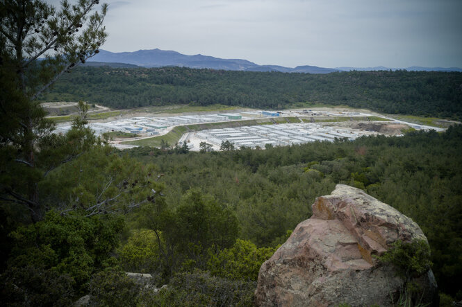 in einer umwaldeten Landschaft steht ein Containerdorf