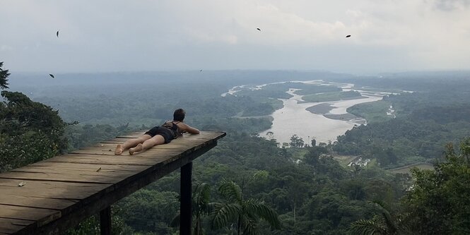 Eine Frau liegt auf einer Aussichtsplattform und blickt über eine Landschaft