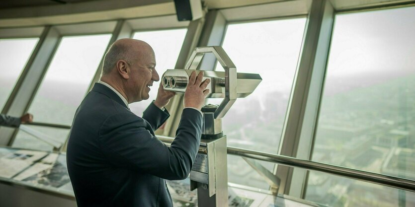 Das Bild zeigt Berlins Regierungschef Kai Wegner (CDU) vor einem Fernglas auf dem Berliner Fernsehturm.