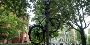 Ein Fahrrad hängt in der Stadt an einer Laterne