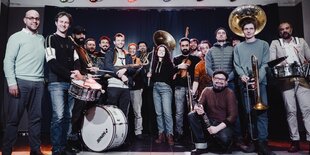 Die 16 Musiker:Innen von Banda Communale mit ihren Instrumenten