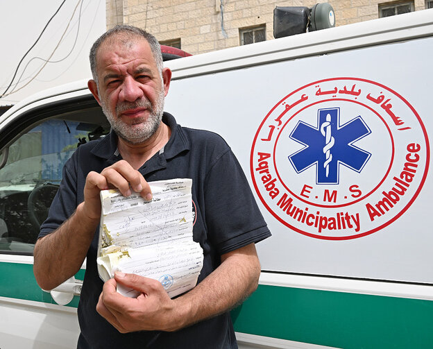 Youssef Diria steht vor einem Rettungswagen und hält ein Dokument in den Händen